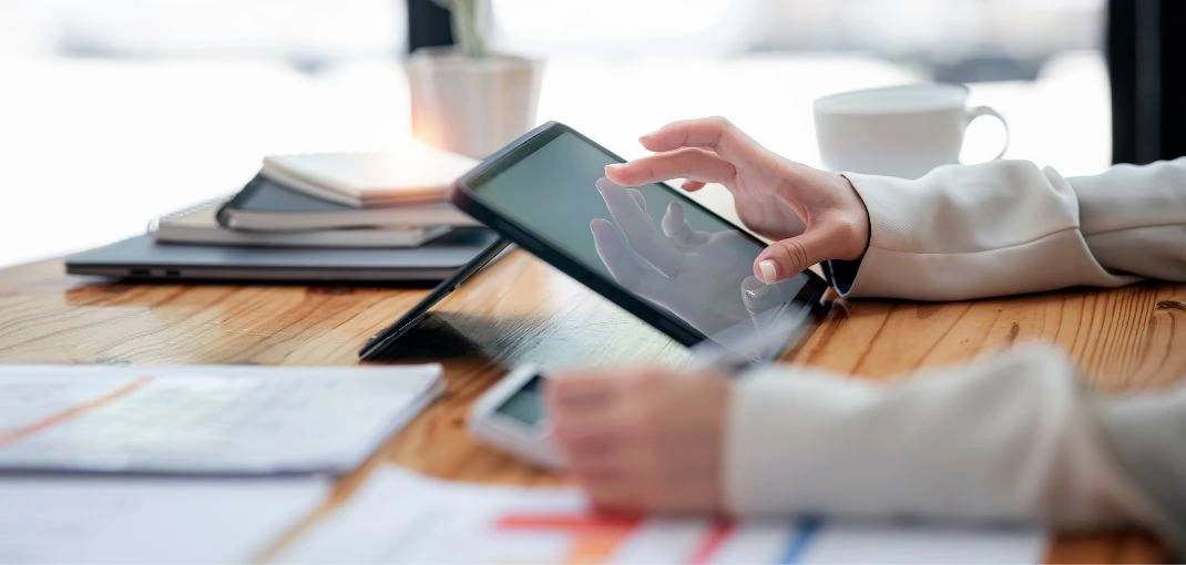 Gros plan du doigt d'une femme d'affaires touchant l'écran d'une tablette numérique alors qu'elle est assise à son bureau.
